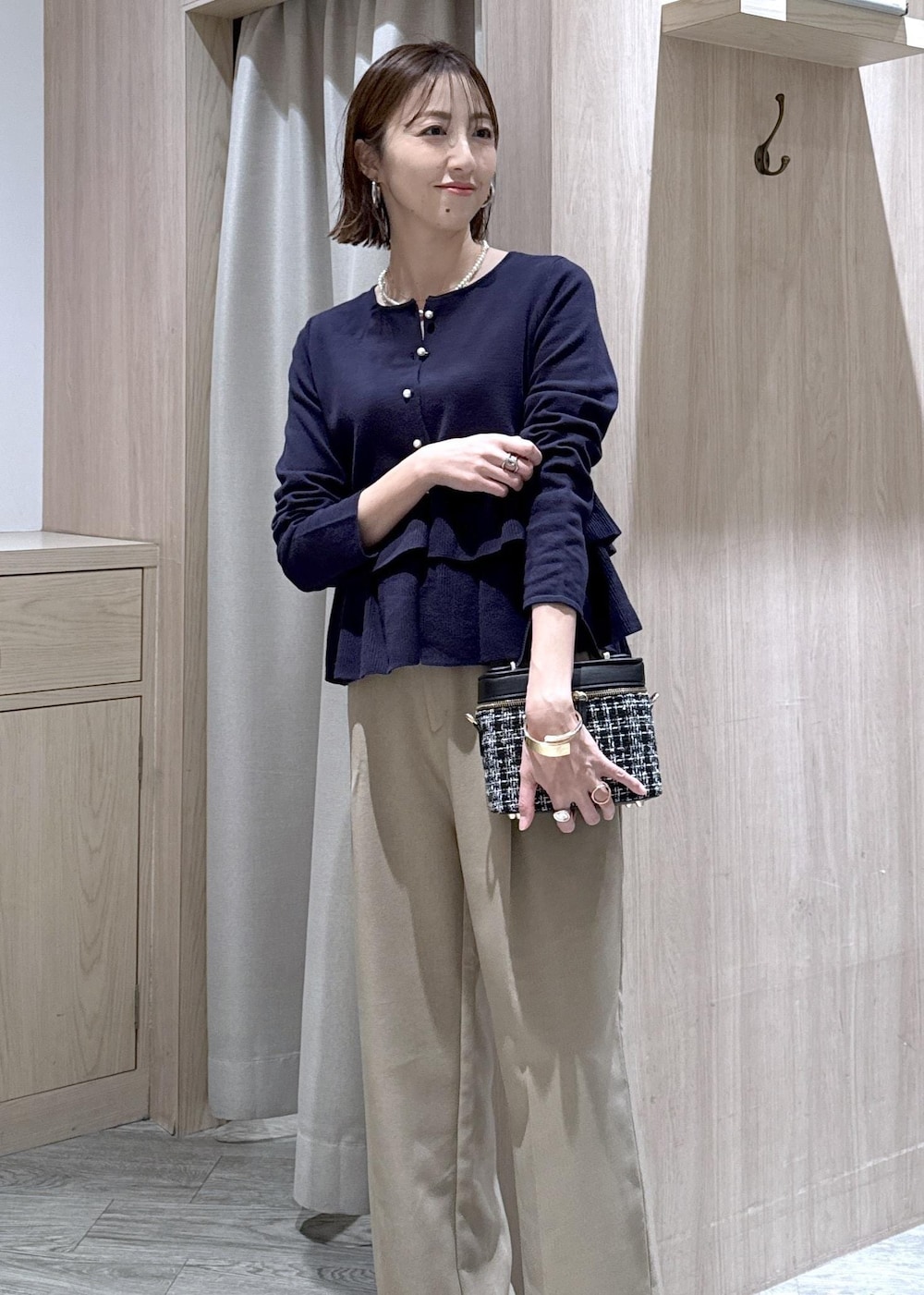 ベージュ系のスラックス、その他のハンドバッグ、ブルー系のカーディガン/ボレロを着用したレディースの冬コーディネートの5枚目の写真