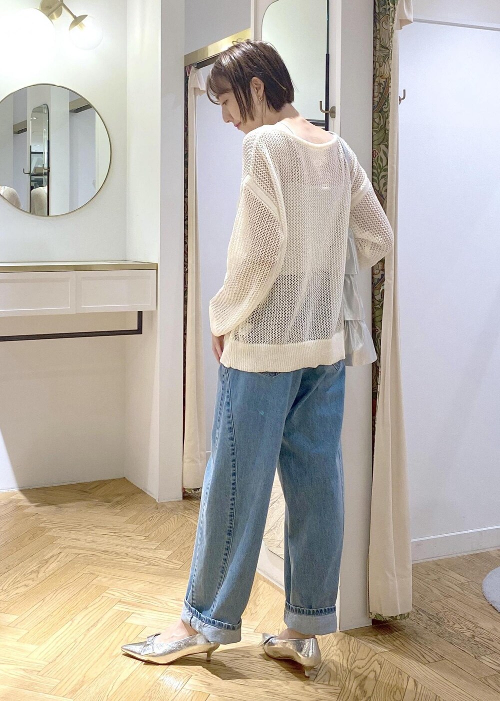 シルバー系のパンプス、シルバー系のトートバッグ、ブルー系のデニムパンツを着用したレディースの夏コーディネートの2枚目の写真