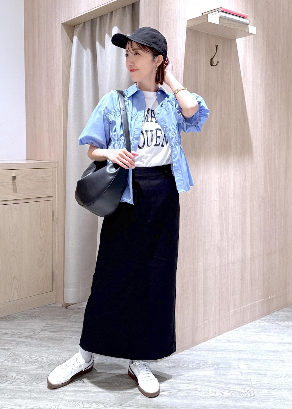 ブラック系のショルダーバッグ、ブラック系のスカート、ホワイト系のTシャツ/カットソーを着用したレディースの春コーディネートの2枚目の写真