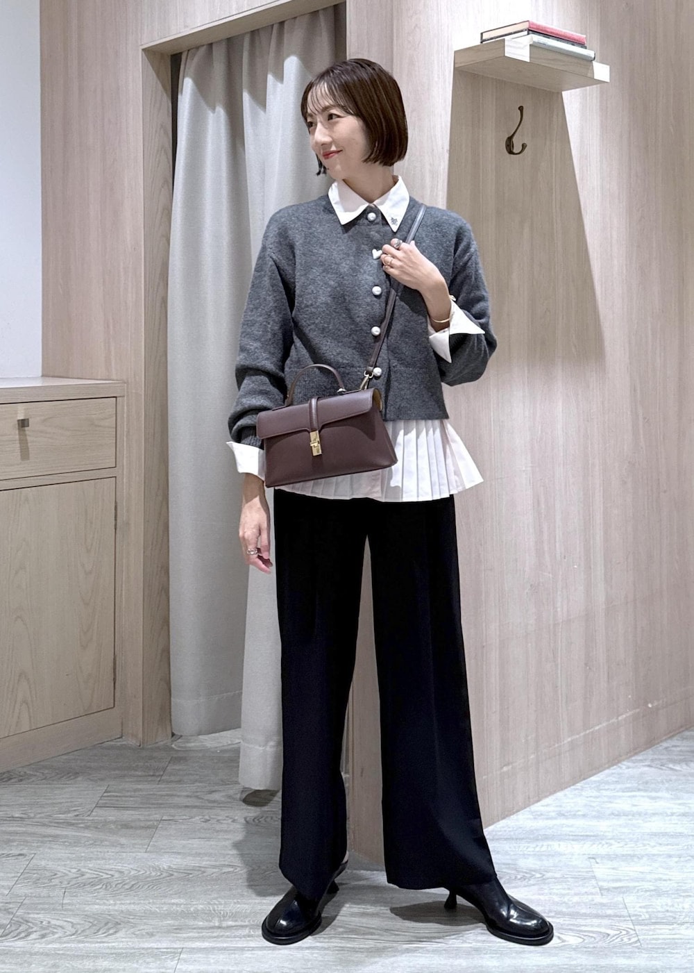 ブラウン系のショルダーバッグ、ブラック系のスラックス、グレー系のカーディガン/ボレロを着用したレディースの秋コーディネートの10枚目の写真