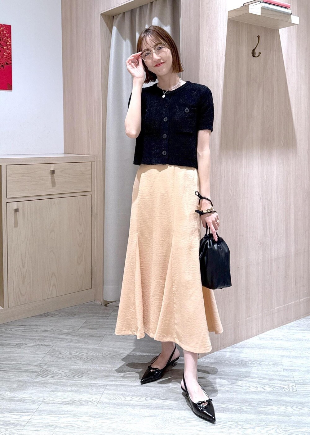 ブラック系のパンプス、オレンジ系のスカート、ブラック系のハンドバッグを着用したレディースの春コーディネートの3枚目の写真