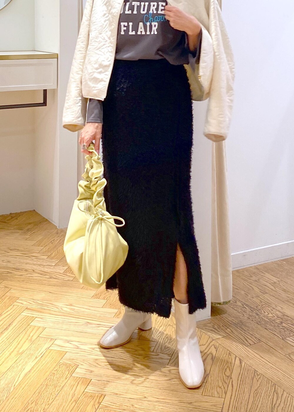 ホワイト系のブーツ、ブラック系のスカート、ホワイト系のブルゾンを着用したレディースの秋コーディネートの4枚目の写真