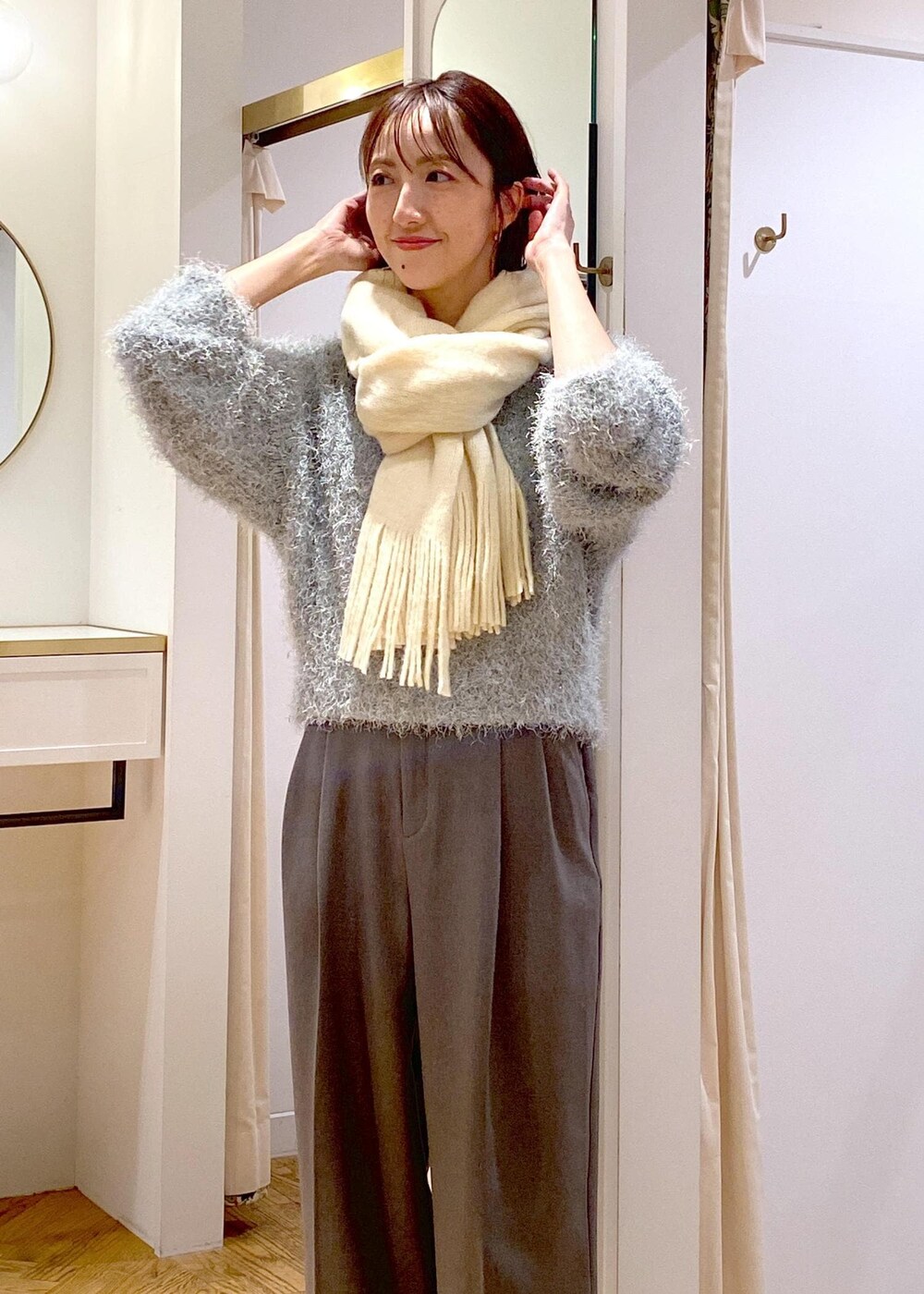 グレー系のスラックス、ブルー系のショルダーバッグ、ブラック系のパンプスを着用したレディースの冬コーディネートの6枚目の写真