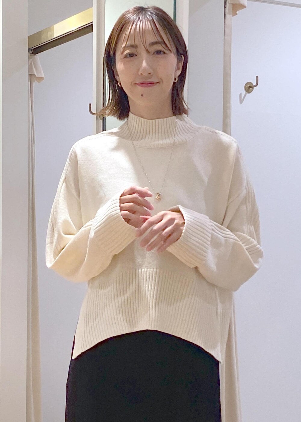 ブラック系のスカート、ホワイト系のニット/セーター、グレー系のショルダーバッグを着用したレディースの秋コーディネートの9枚目の写真