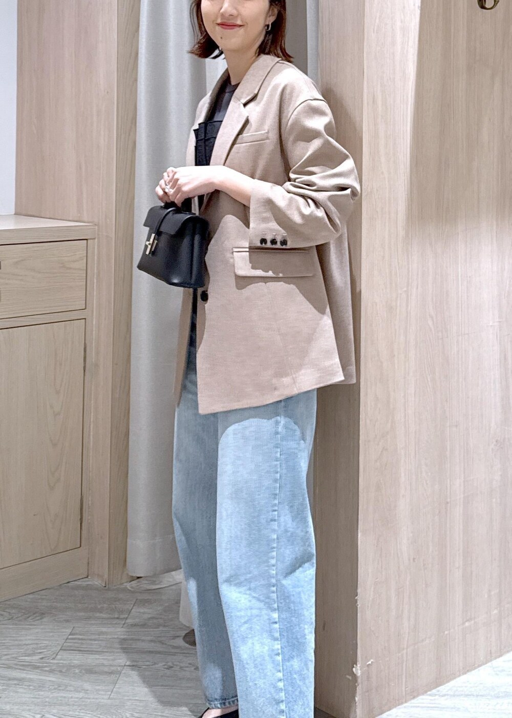 ブラック系のショルダーバッグ、ブルー系のデニムパンツ、イエロー系のテーラードジャケットを着用したレディースの春コーディネートの5枚目の写真