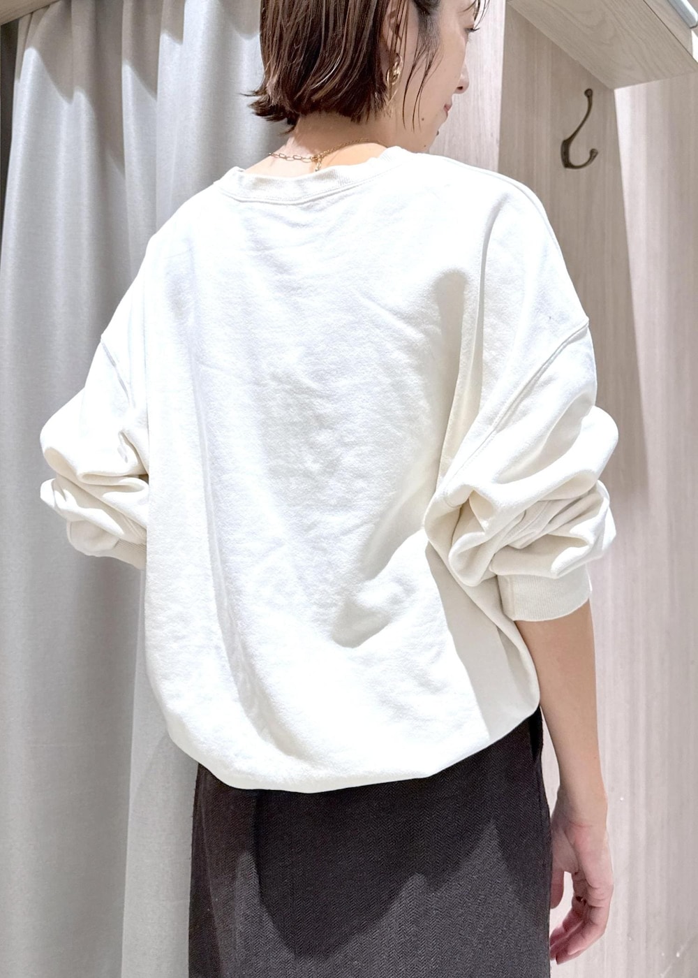 ブラウン系のショルダーバッグ、ブラック系のブーツ、ホワイト系のブルゾンを着用したレディースの秋コーディネートの9枚目の写真