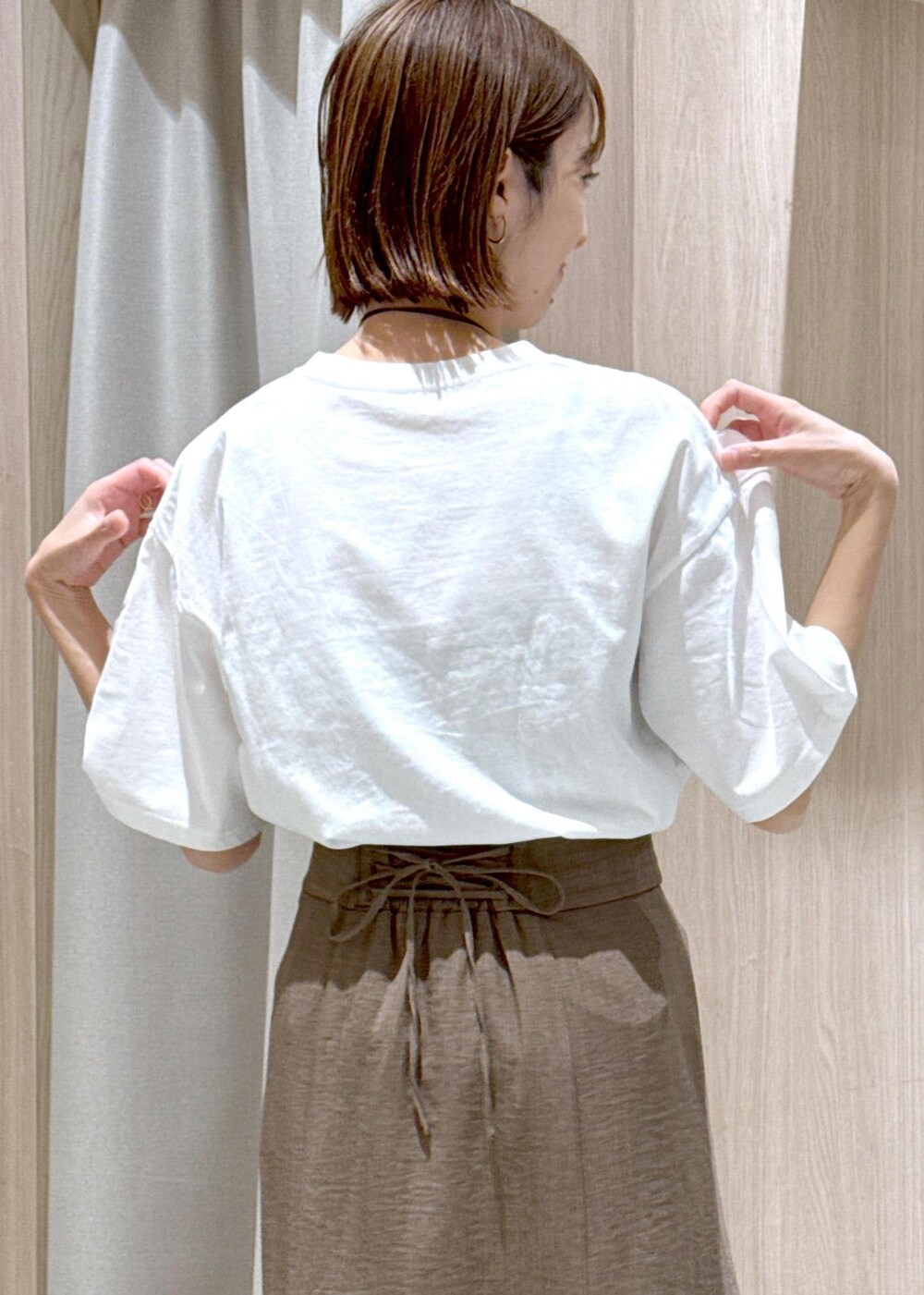 グリーン系のスカート、ホワイト系のTシャツ/カットソー、ブラック系のハンドバッグを着用したレディースの春コーディネートの10枚目の写真