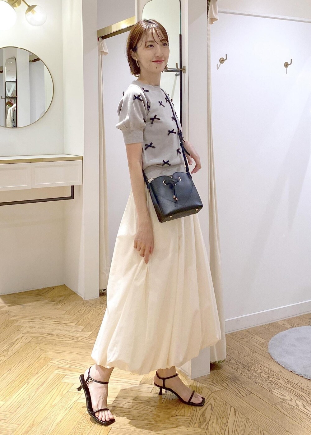 ブラック系のサンダル、ホワイト系のスカート、ブラック系のキャミソールを着用したレディースの夏コーディネートの2枚目の写真