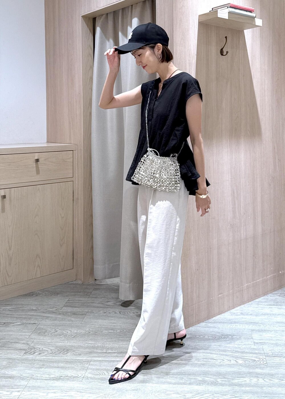 ブラック系のサンダル、ブラック系のシャツ/ブラウス、ホワイト系のスラックスを着用したレディースの夏コーディネートの3枚目の写真