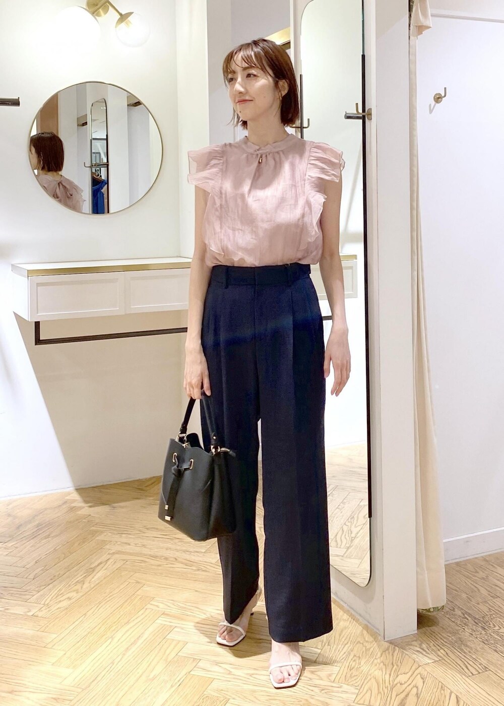 ブルー系のスラックス、ブラック系のハンドバッグ、ホワイト系のキャミソールを着用したレディースの春コーディネートの6枚目の写真