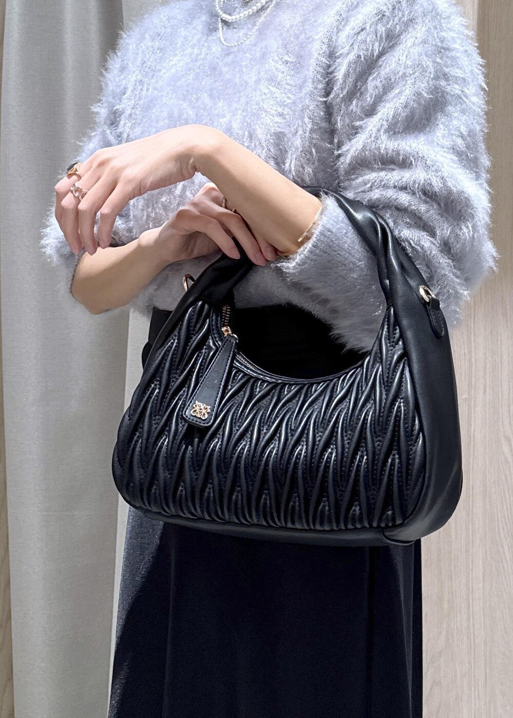ブラック系のハンドバッグ、ブラック系のスカート、ブルー系のニット/セーターを着用したレディースの冬コーディネートの8枚目の写真