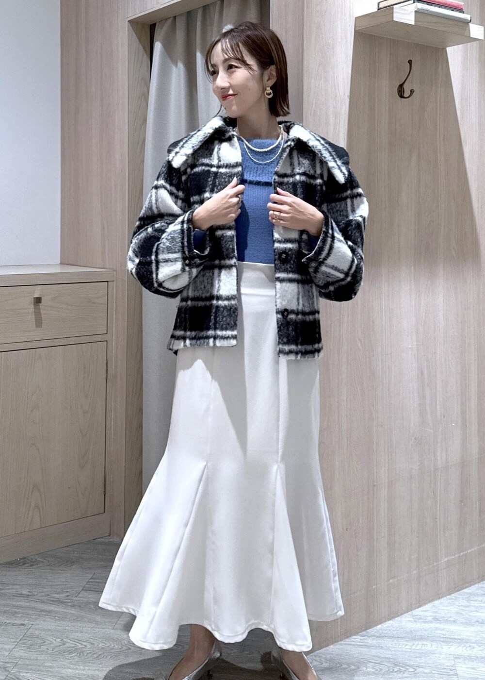 シルバー系のパンプス、ホワイト系のハンドバッグ、ブルー系のニット/セーターを着用したレディースの秋コーディネートの6枚目の写真