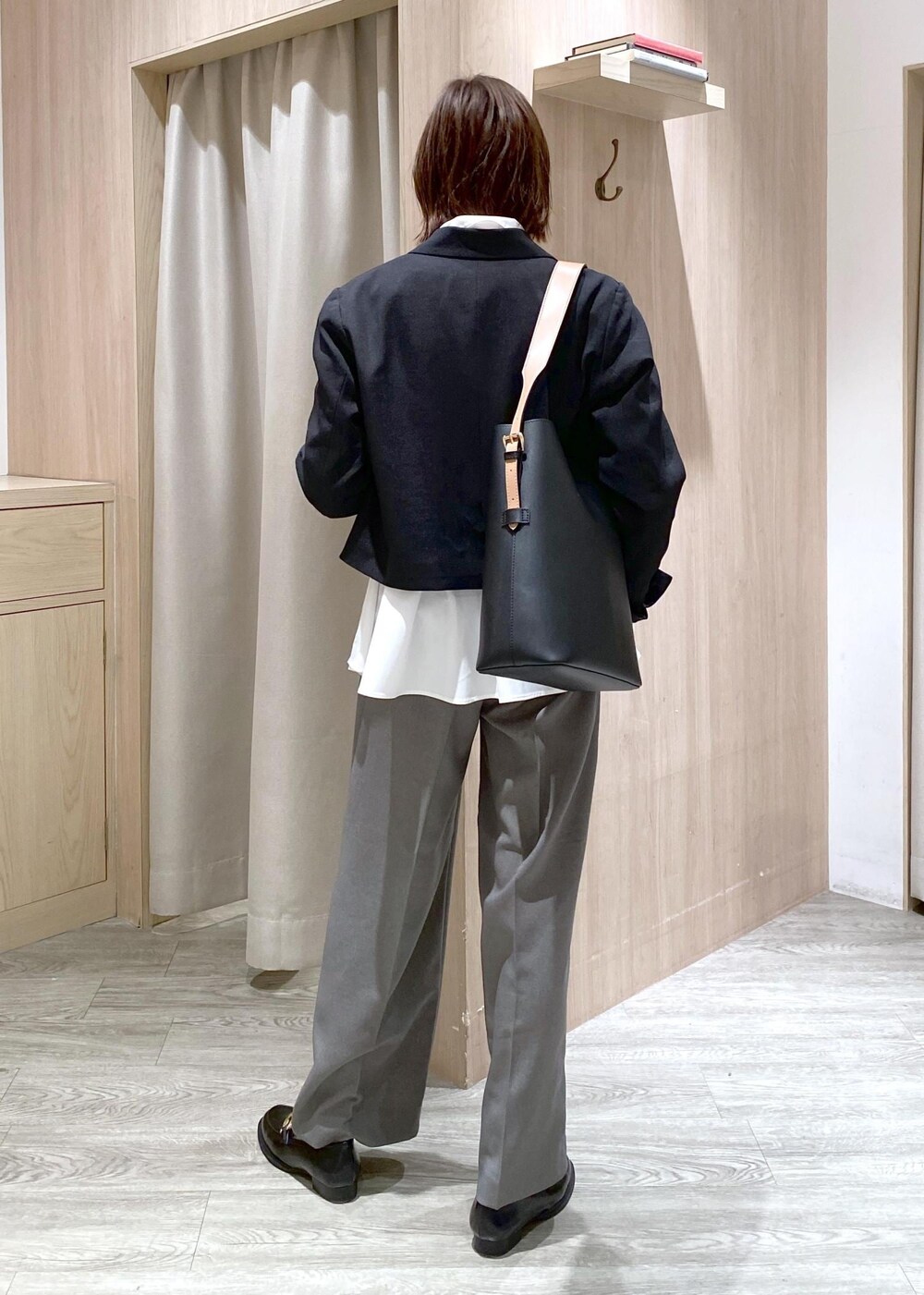 ブラック系のショルダーバッグ、グレー系のスラックス、ホワイト系のカーディガン/ボレロを着用したレディースの冬コーディネートの3枚目の写真