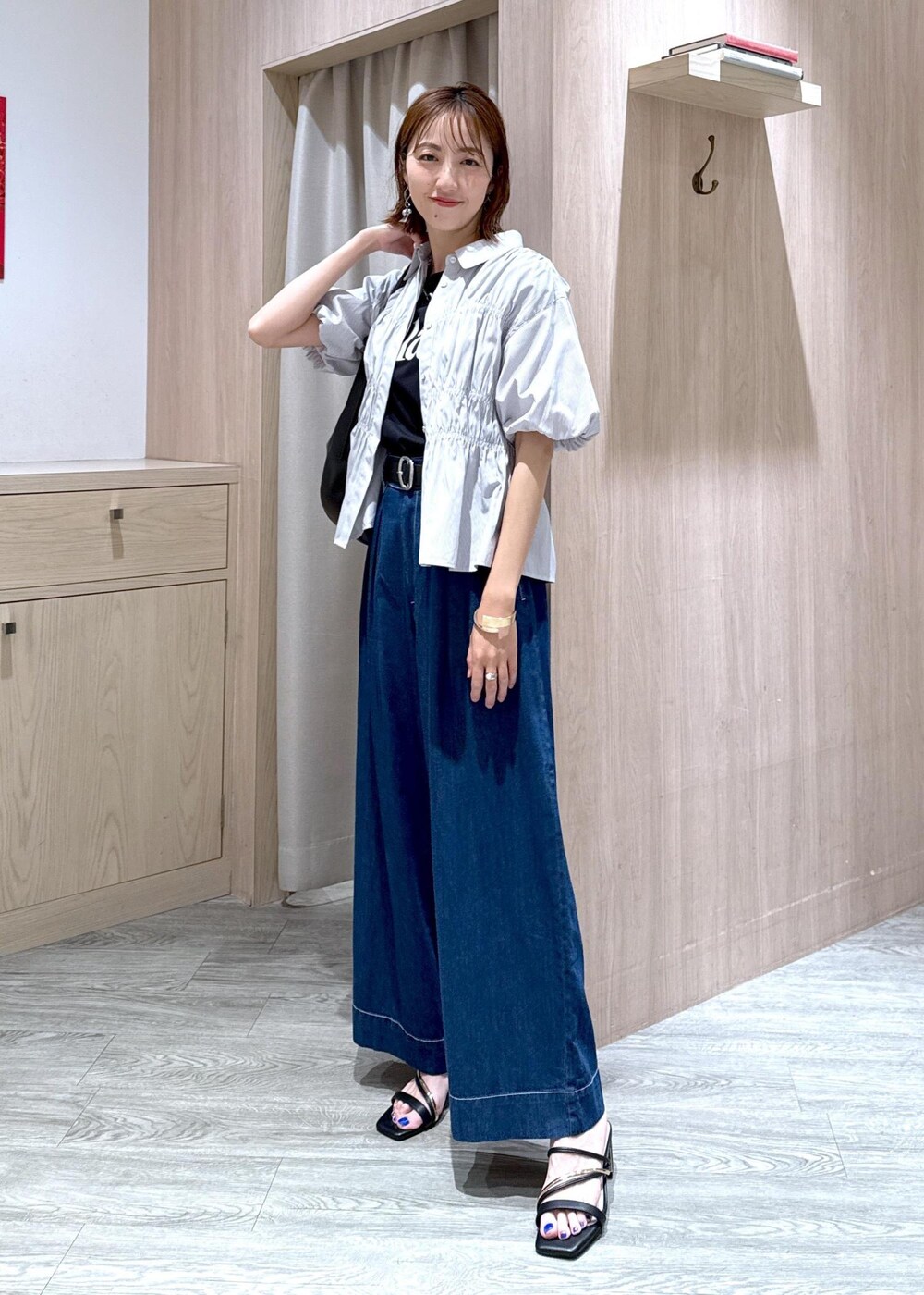 ブラック系のショルダーバッグ、ブラック系のサンダル、ブルー系のデニムパンツを着用したレディースの夏コーディネートの4枚目の写真