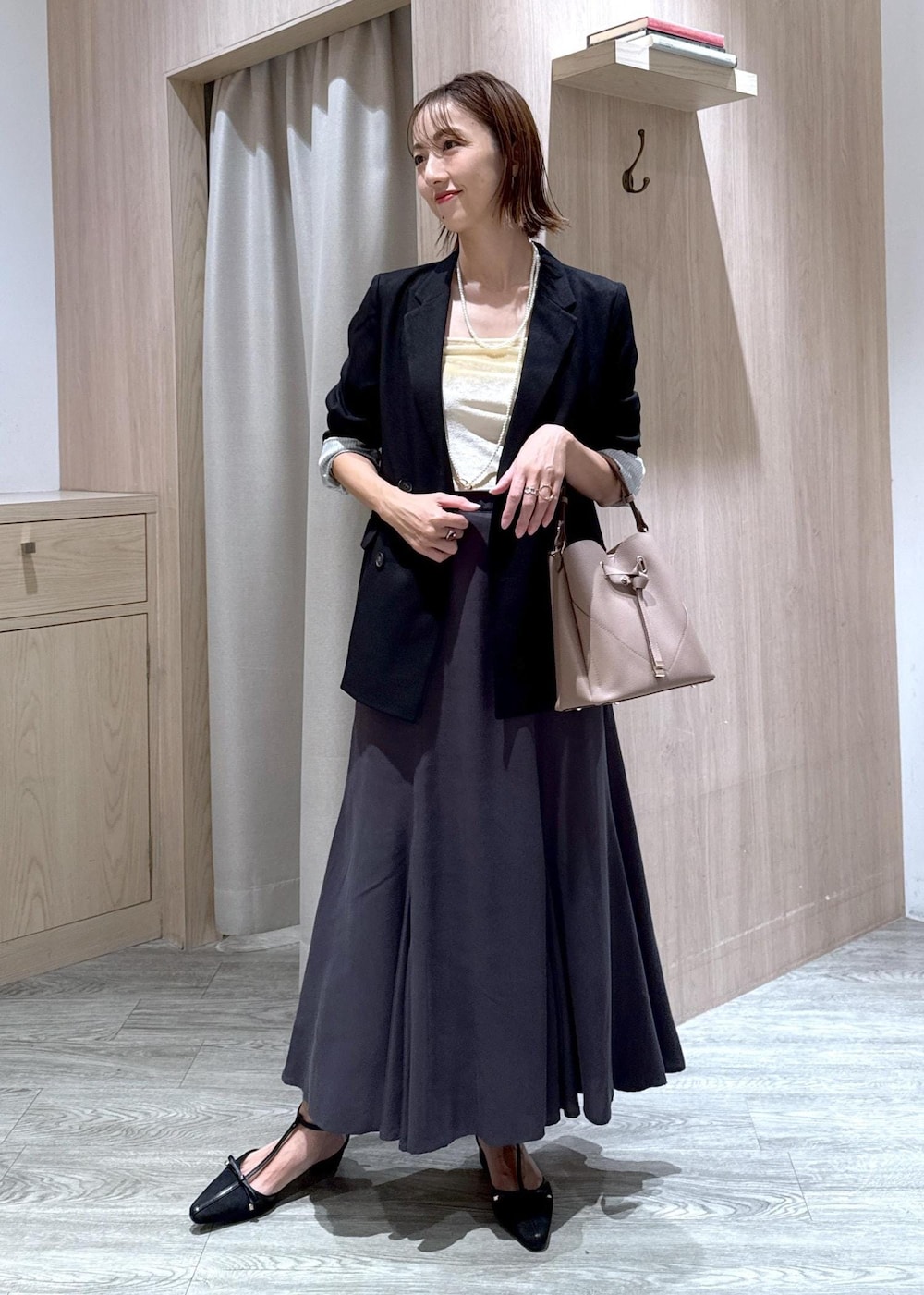 ブラック系のパンプス、ブラック系のテーラードジャケット、ベージュ系のショルダーバッグを着用したレディースの秋コーディネートの2枚目の写真