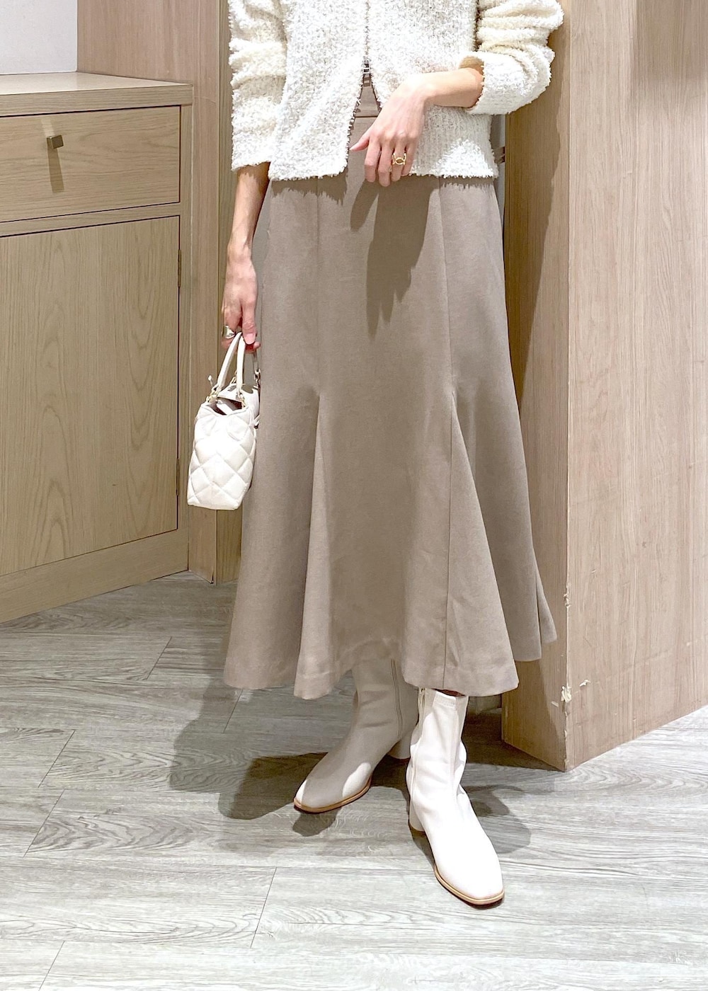 ホワイト系のブーツ、ベージュ系のスカート、ホワイト系のカーディガン/ボレロを着用したレディースの冬コーディネートの7枚目の写真