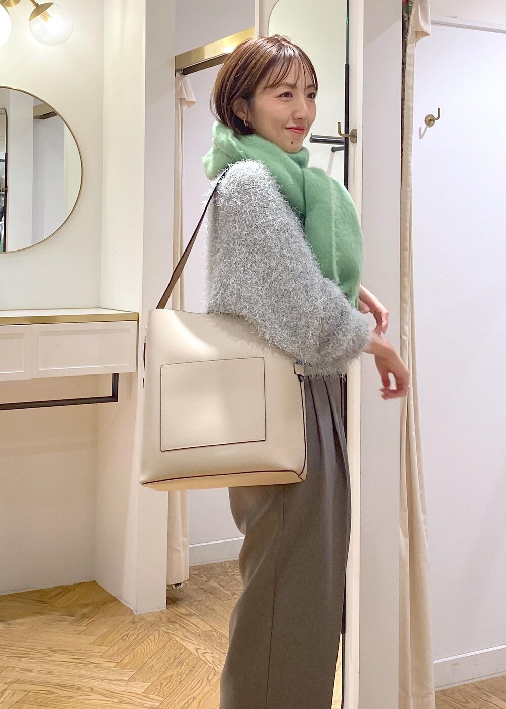 ベージュ系のショルダーバッグ、グレー系のスラックス、グリーン系のニット/セーターを着用したレディースの冬コーディネートの4枚目の写真