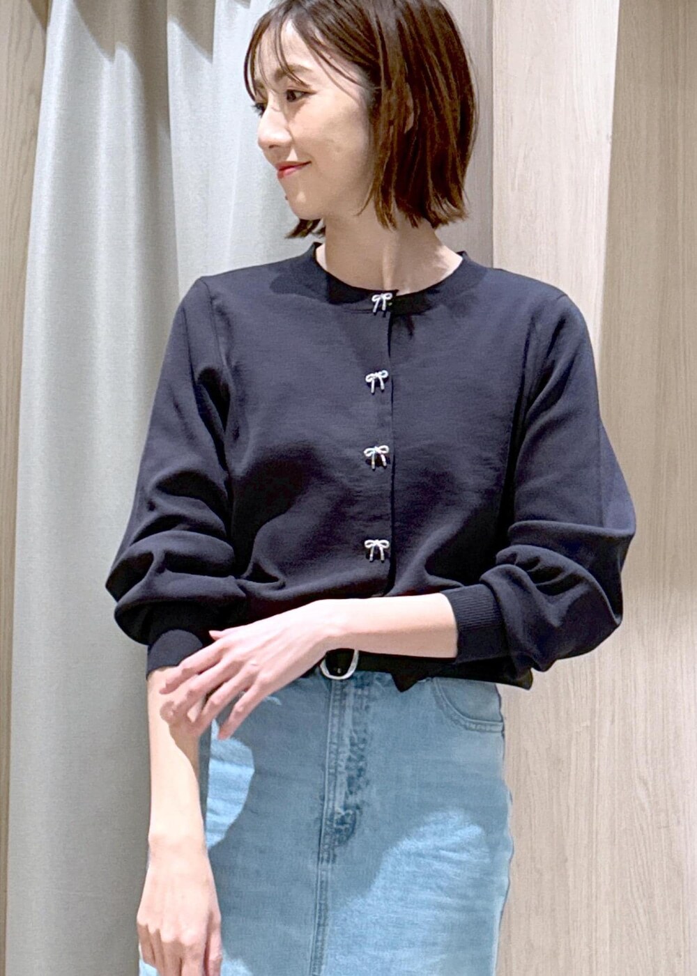 ブラック系のショルダーバッグ、ブルー系のデニムスカート、グレー系のカーディガン/ボレロを着用したレディースの冬コーディネートの6枚目の写真