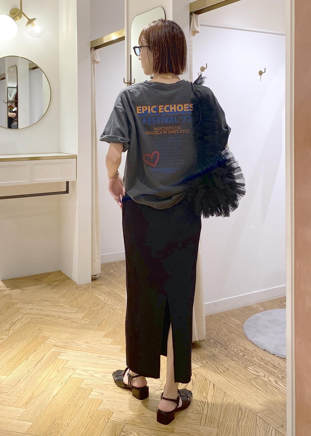 ブラック系のショルダーバッグ、ブラック系のスカート、グレー系のTシャツ/カットソーを着用したレディースの夏コーディネートの2枚目の写真