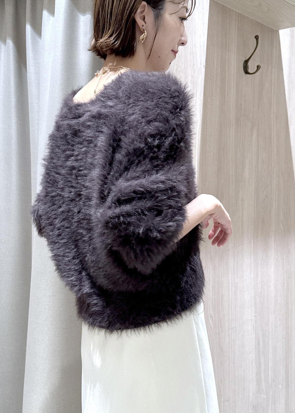 ブラック系のブーツ、ホワイト系のスカート、グレー系のカーディガン/ボレロを着用したレディースの冬コーディネートの7枚目の写真