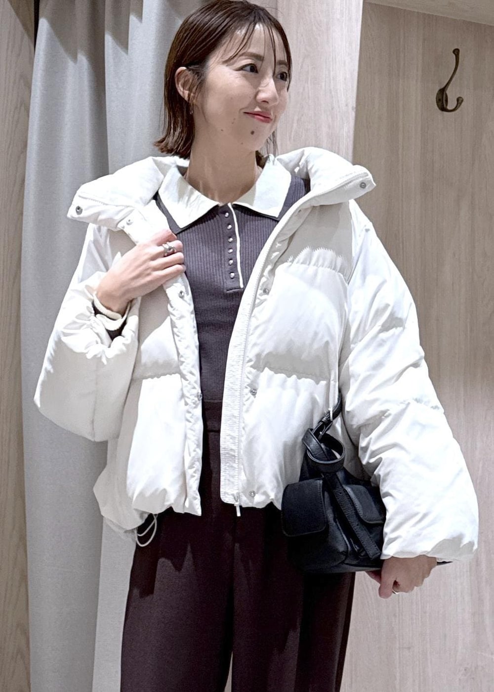 ブラウン系のスラックス、ブラック系のショルダーバッグ、ホワイト系のダウンジャケット/コートを着用したレディースの冬コーディネートの9枚目の写真