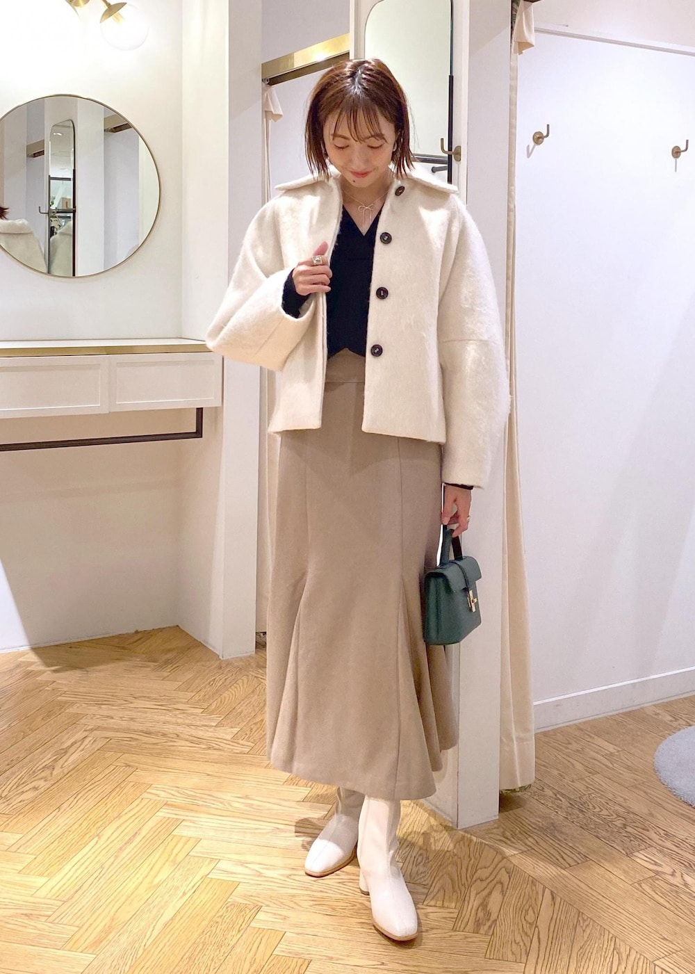 ホワイト系のブーツ、ベージュ系のスカート、ホワイト系のその他アウターを着用したレディースの秋コーディネートの4枚目の写真