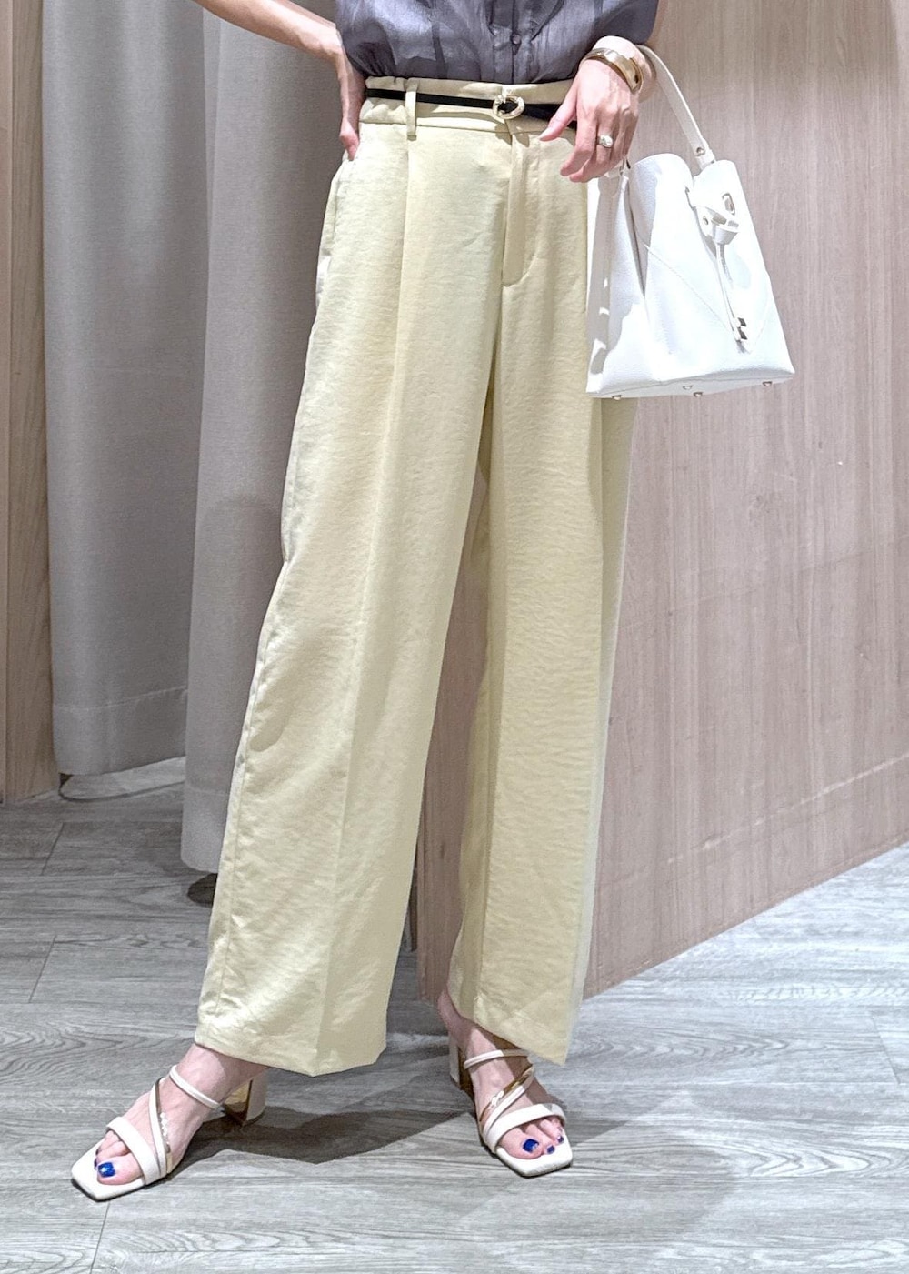 ホワイト系のショルダーバッグ、ホワイト系のサンダル、イエロー系のスラックスを着用したレディースの夏コーディネートの4枚目の写真