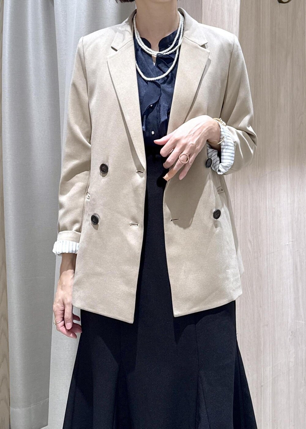 ブラック系のハンドバッグ、ブルー系のシャツ/ブラウス、ベージュ系のテーラードジャケットを着用したレディースの秋コーディネートの6枚目の写真