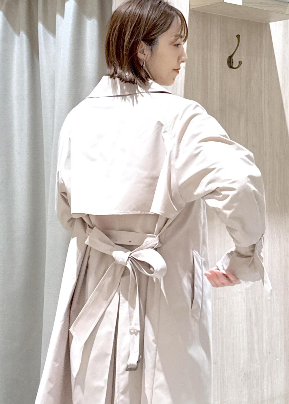 ブラック系のショルダーバッグ、ベージュ系のトレンチコート、ホワイト系のカーディガン/ボレロを着用したレディースの春コーディネートの5枚目の写真