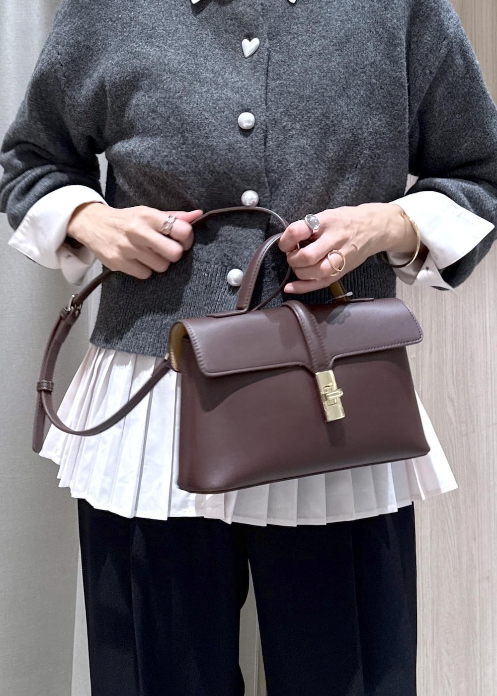 ブラウン系のショルダーバッグ、ブラック系のスラックス、グレー系のカーディガン/ボレロを着用したレディースの秋コーディネートの9枚目の写真