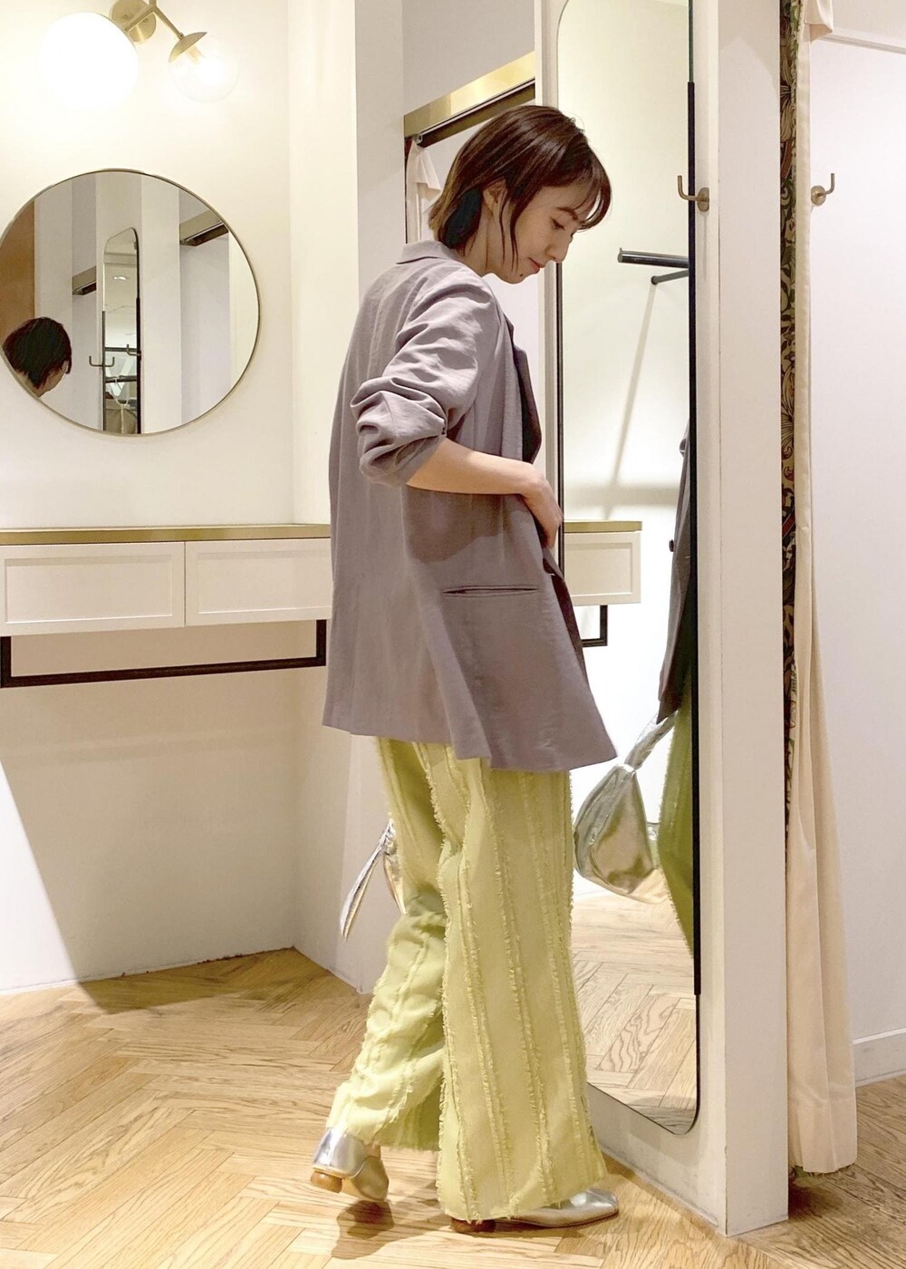 シルバー系のパンプス、グリーン系のスラックス、シルバー系のハンドバッグを着用したレディースの春コーディネートの3枚目の写真