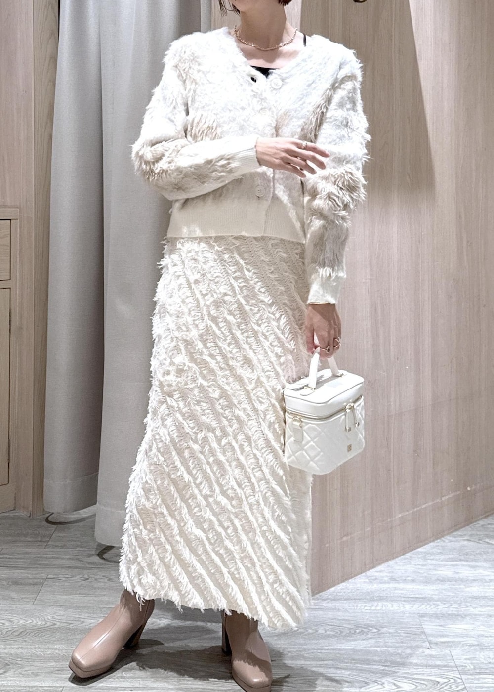 ホワイト系のスカート、ベージュ系のブーツ、ホワイト系のハンドバッグを着用したレディースの秋コーディネートの3枚目の写真