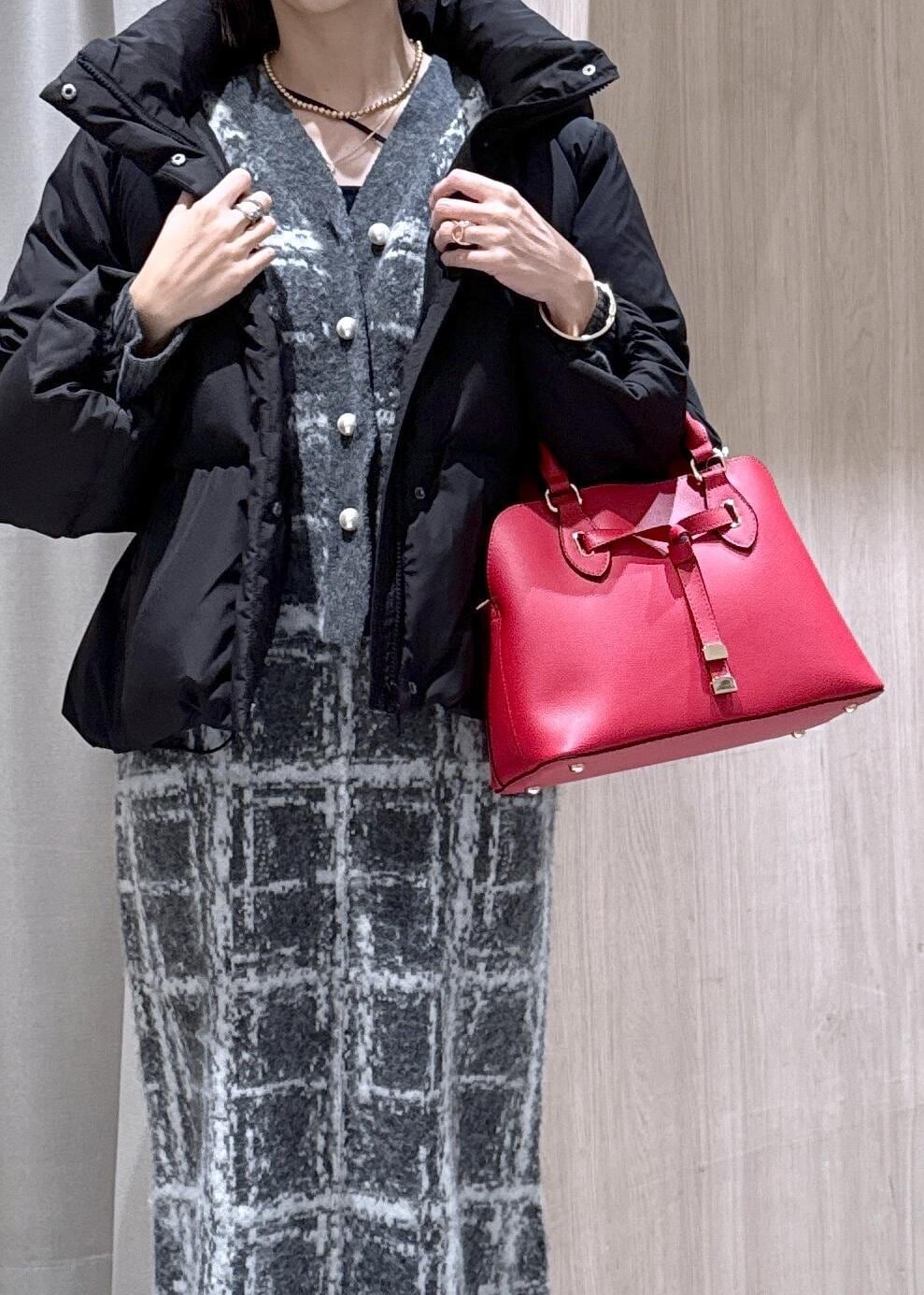 レッド系のボストンバッグ、ブラック系のダウンジャケット/コート、グレー系のスカートを着用したレディースの冬コーディネートの7枚目の写真
