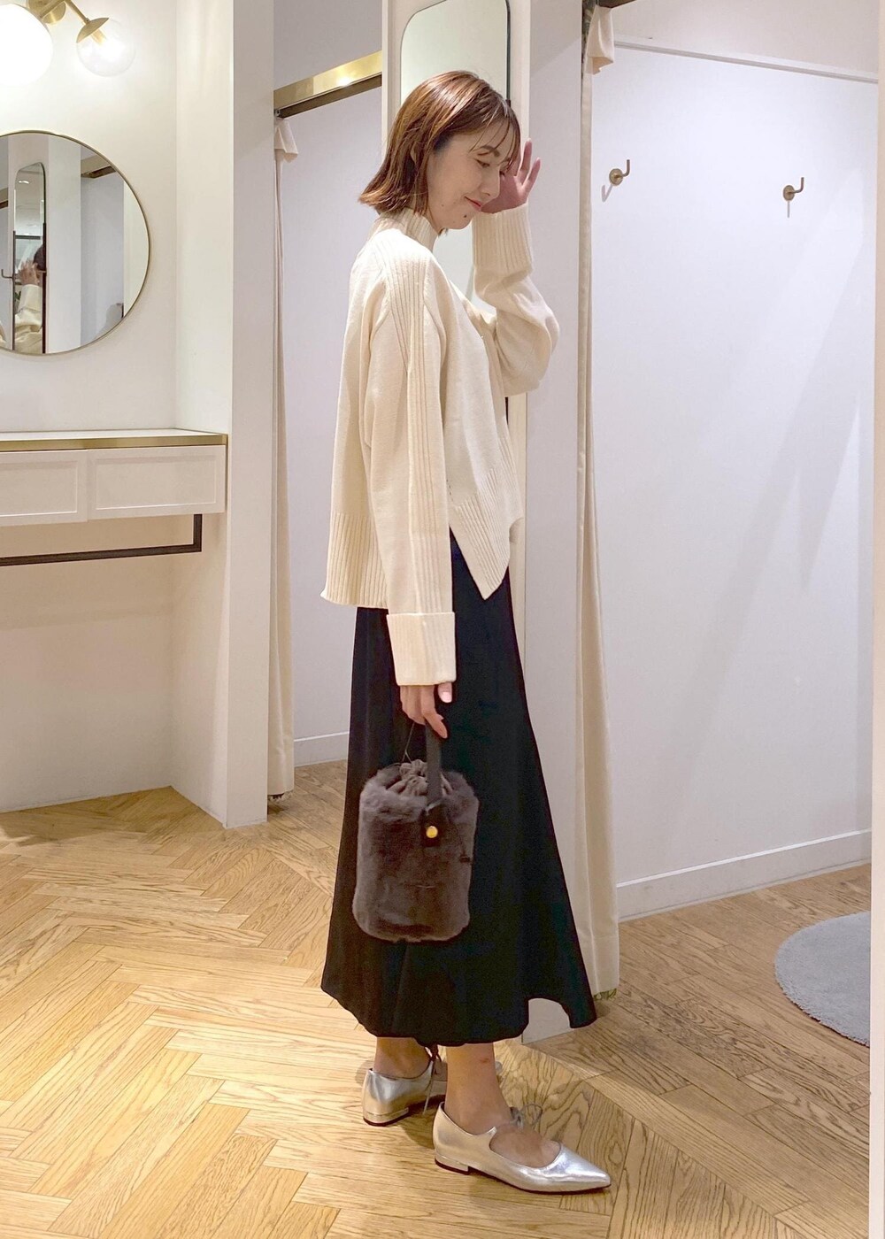 ブラック系のスカート、ホワイト系のニット/セーター、グレー系のショルダーバッグを着用したレディースの秋コーディネートの2枚目の写真