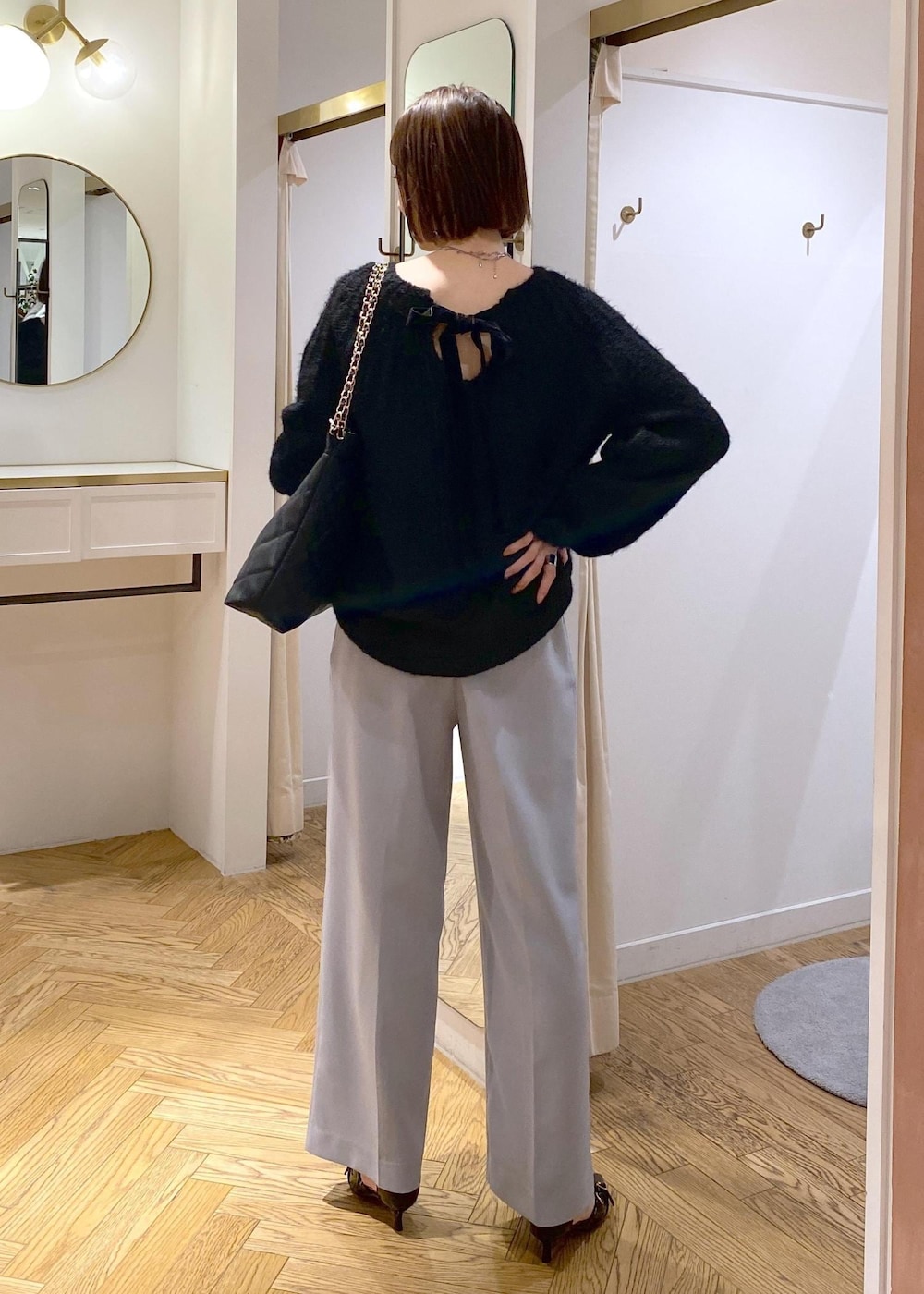 ブルー系のスラックス、ブラック系のパンプス、ブラック系のショルダーバッグを着用したレディースの冬コーディネートの5枚目の写真