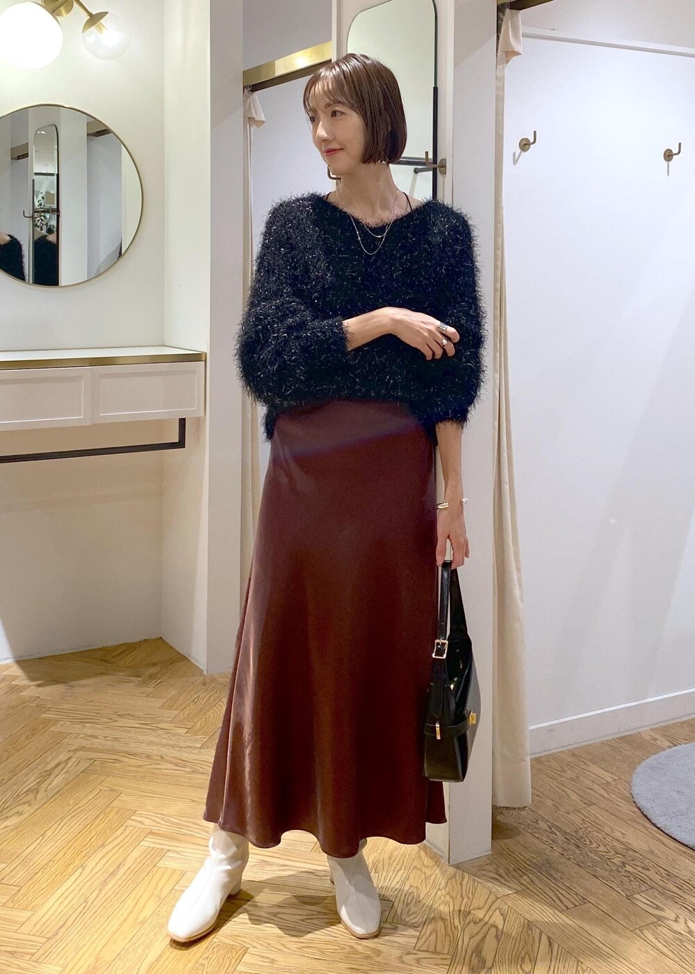 ホワイト系のブーツ、ブラック系のハンドバッグ、ブラック系のニット/セーターを着用したレディースの冬コーディネートの8枚目の写真