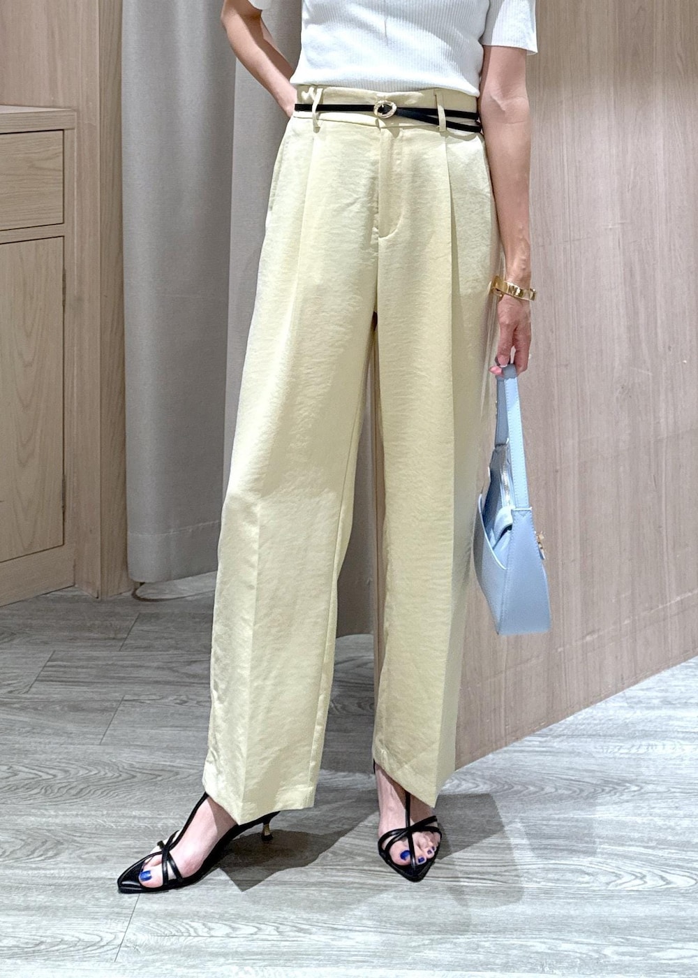 ブルー系のハンドバッグ、ブラック系のサンダル、イエロー系のスラックスを着用したレディースの夏コーディネートの6枚目の写真