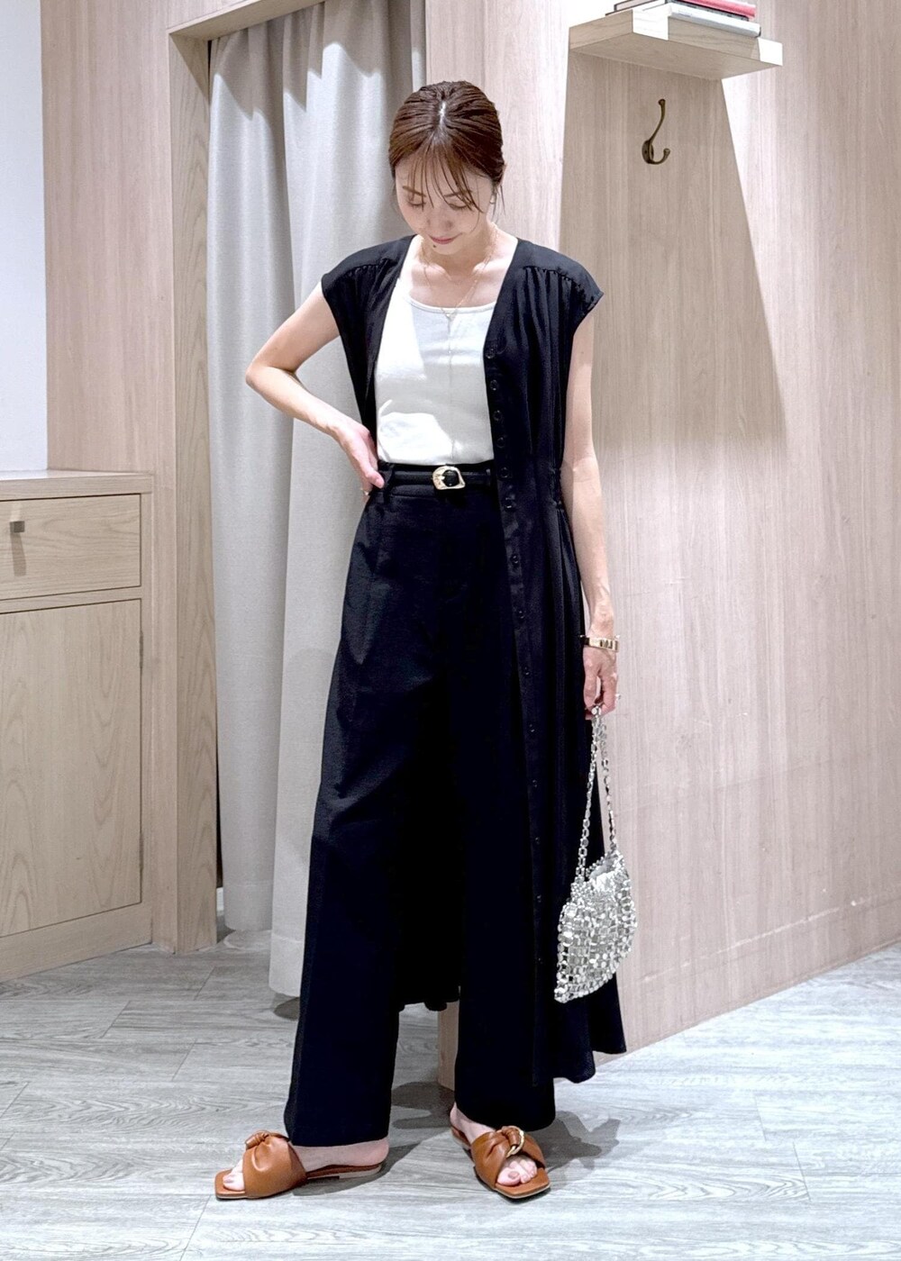 ホワイト系のタンクトップ、ブラック系のスラックス、シルバー系のハンドバッグを着用したレディースの春コーディネートの2枚目の写真