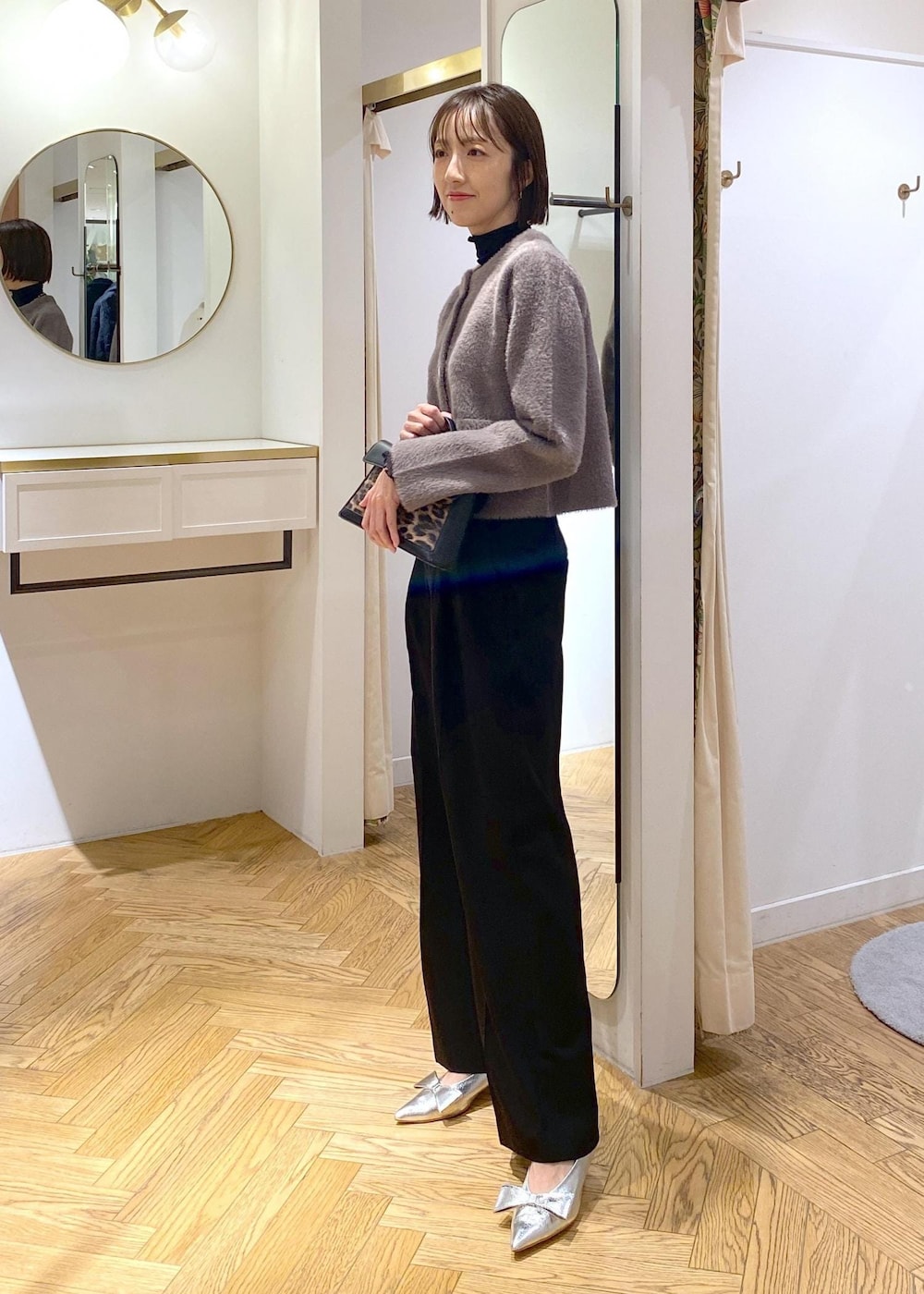 シルバー系のパンプス、ブラウン系のカーディガン/ボレロ、ブラック系のTシャツ/カットソーを着用したレディースの冬コーディネートの2枚目の写真