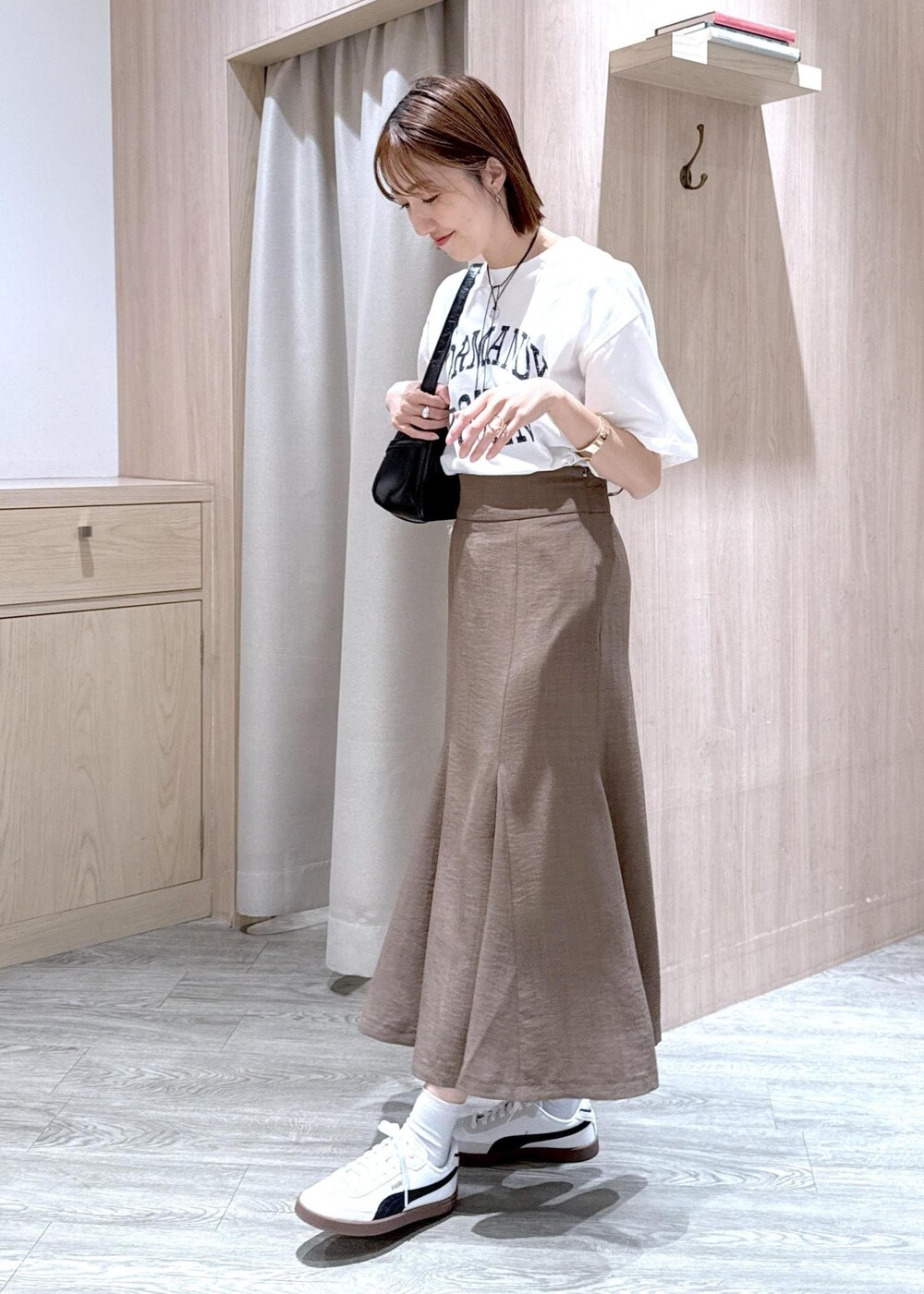 グリーン系のスカート、ホワイト系のTシャツ/カットソー、ブラック系のハンドバッグを着用したレディースの春コーディネートの2枚目の写真