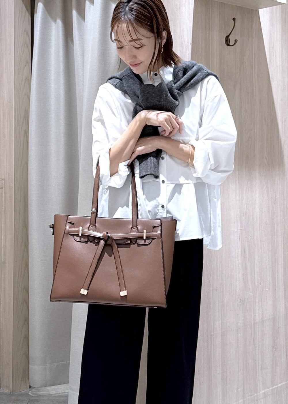 ブラウン系のトートバッグ、ホワイト系のシャツ/ブラウス、ブラック系のスラックスを着用したレディースの秋コーディネートの4枚目の写真