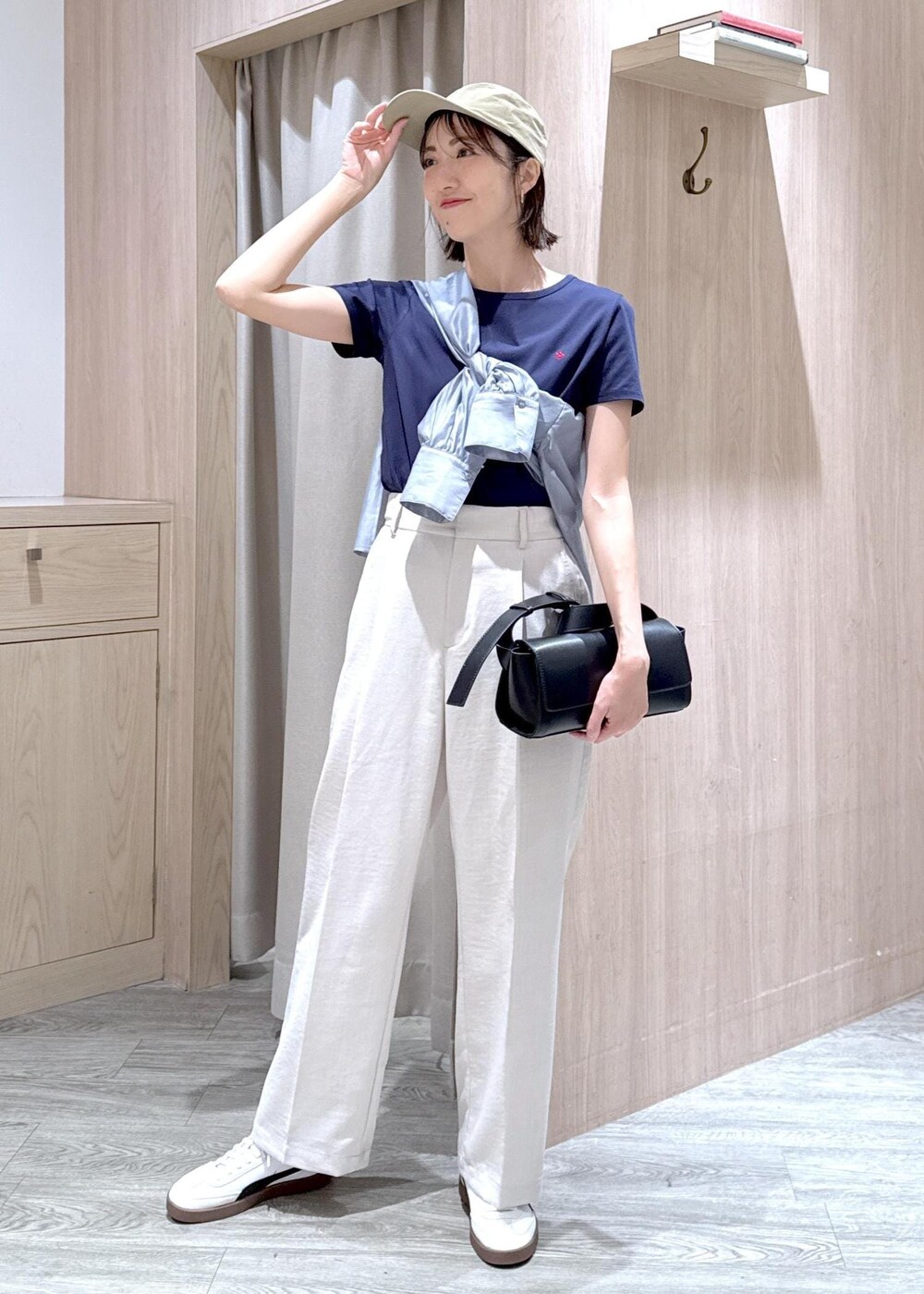 ブラック系のショルダーバッグ、グレー系のシャツ/ブラウス、ホワイト系のスラックスを着用したレディースの春コーディネートの2枚目の写真