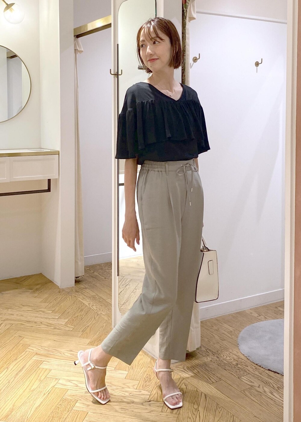 グリーン系のスラックス、ホワイト系のサンダル、ホワイト系のハンドバッグを着用したレディースの夏コーディネートの4枚目の写真