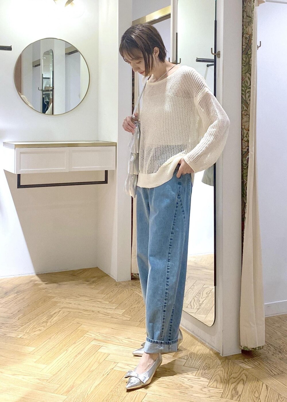 シルバー系のパンプス、シルバー系のトートバッグ、ブルー系のデニムパンツを着用したレディースの夏コーディネートの6枚目の写真