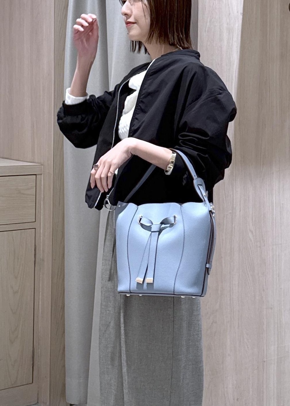 ブルー系のショルダーバッグ、ホワイト系のパンプス、ブラック系のブルゾンを着用したレディースの春コーディネートの9枚目の写真