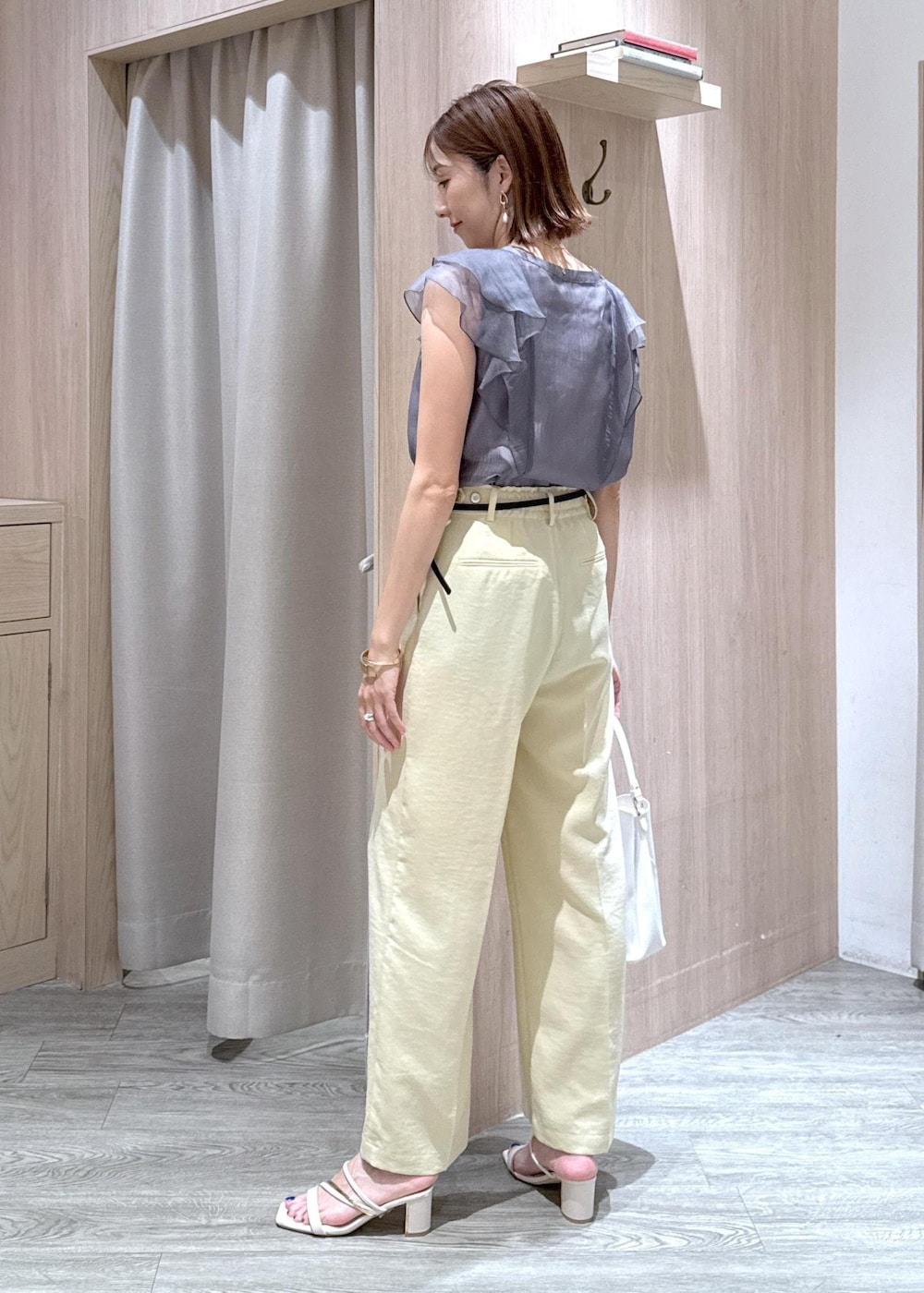 ホワイト系のショルダーバッグ、ホワイト系のサンダル、イエロー系のスラックスを着用したレディースの夏コーディネートの2枚目の写真