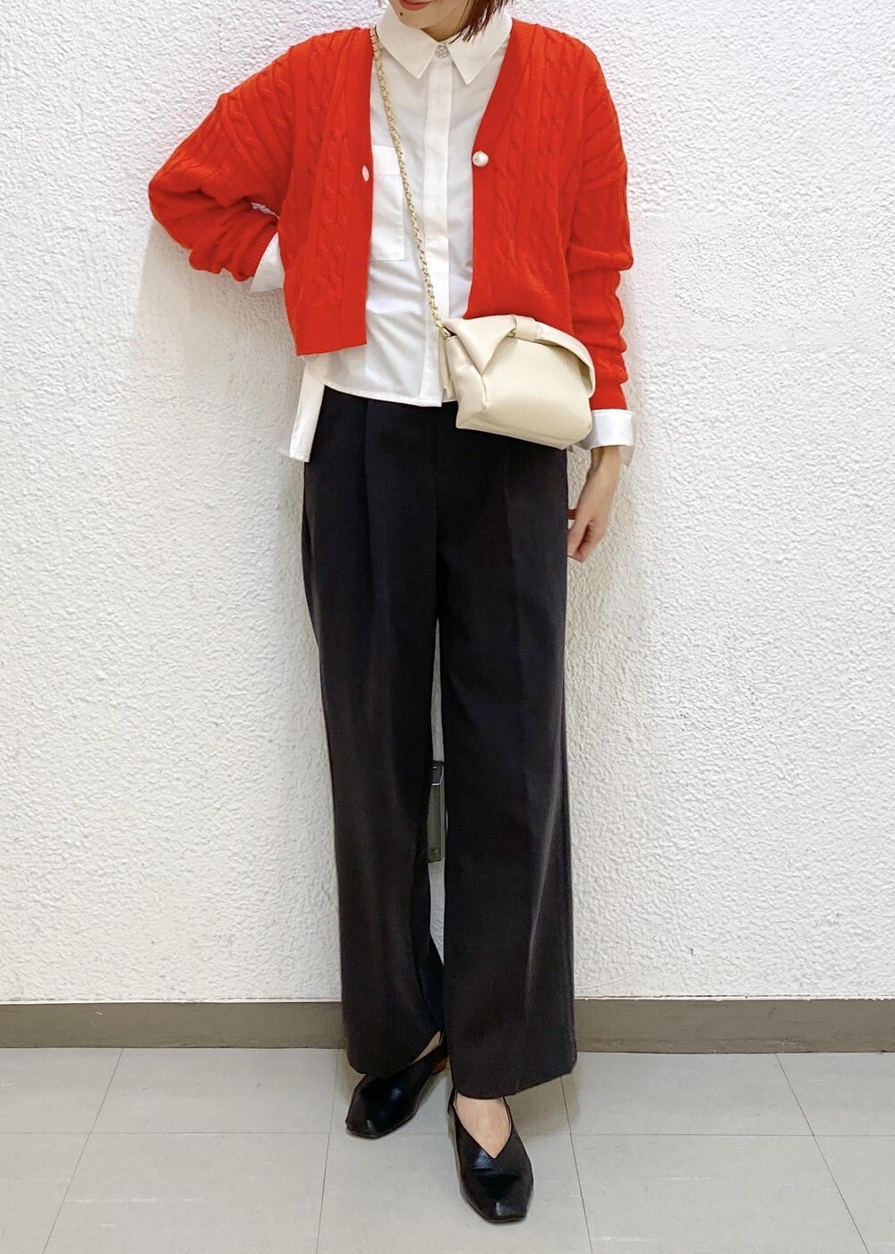 グレー系のスラックス、ホワイト系のシャツ/ブラウス、オレンジ系のカーディガン/ボレロを着用したレディースの冬コーディネートの3枚目の写真