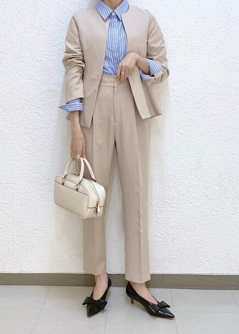 ブラック系のパンプス、ブルー系のシャツ/ブラウス、ベージュ系のノーカラージャケットを着用したレディースの冬コーディネートの3枚目の写真