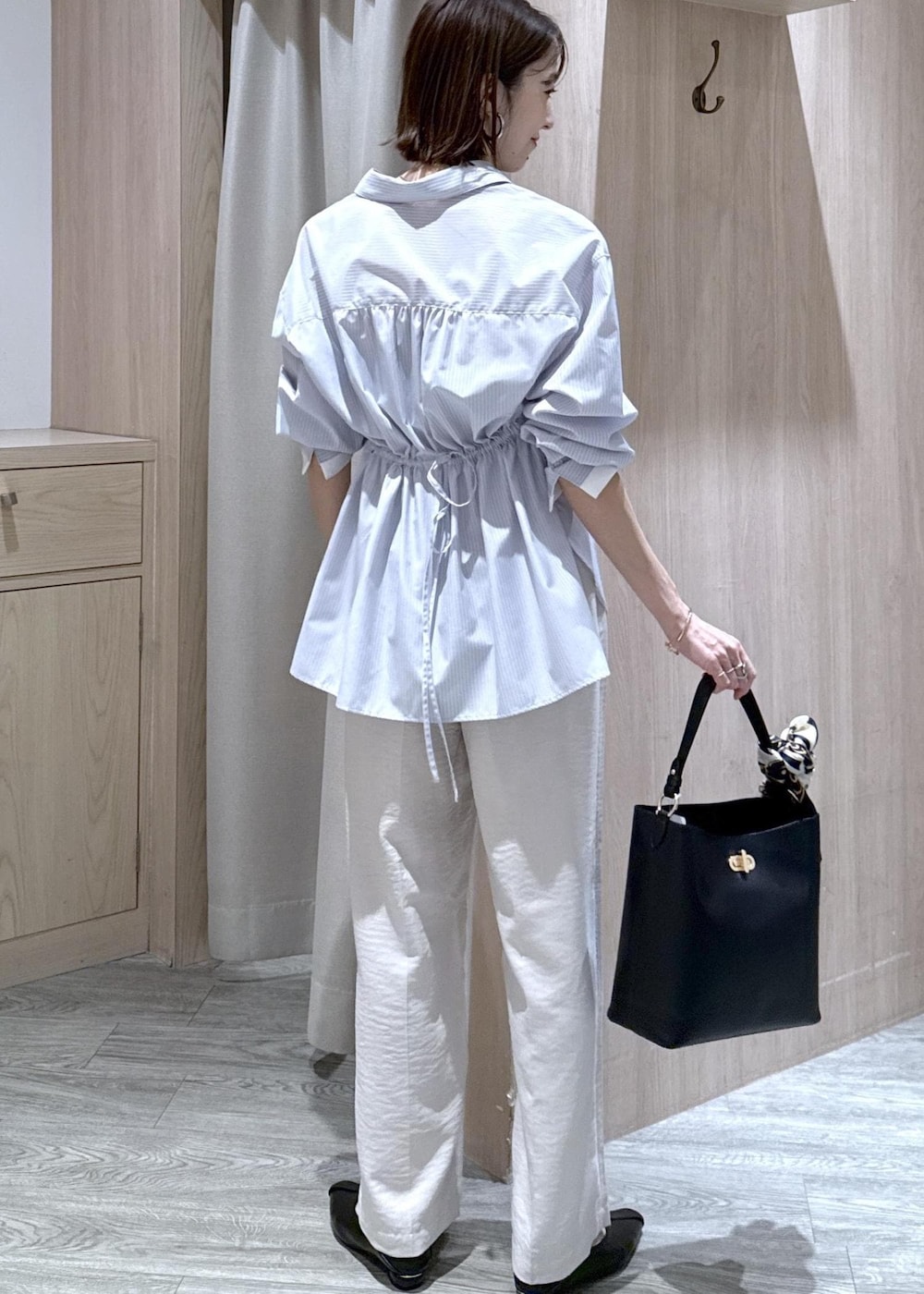 ベージュ系のキャミソール、ブラック系のショルダーバッグ、ブルー系のシャツ/ブラウスを着用したレディースの春コーディネートの3枚目の写真