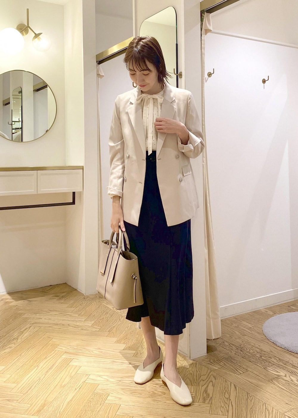 ベージュ系のトートバッグ、ホワイト系のパンプス、ホワイト系のシャツ/ブラウスを着用したレディースの春コーディネートの2枚目の写真